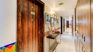 A hotel hallway with wooden doors, numbered room signs, framed artwork, and a tiled accent wall. - Fabhotel The Perfect (Lucknow)