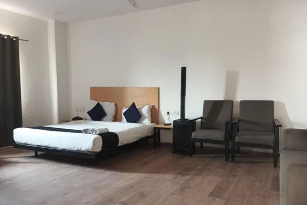 Een hotelkamer met een bed, een stoel, een nachtkastje en een verwarming.
