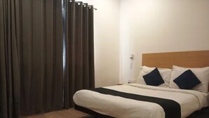 A hotel room with a bed, curtains, a wooden floor, and a nightstand. - Fabhotel Yash Meridion (Jaipur)
