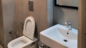A bathroom with a toilet, sink, and mirror. - Fabhotel Yash Meridion (Jaipur)
