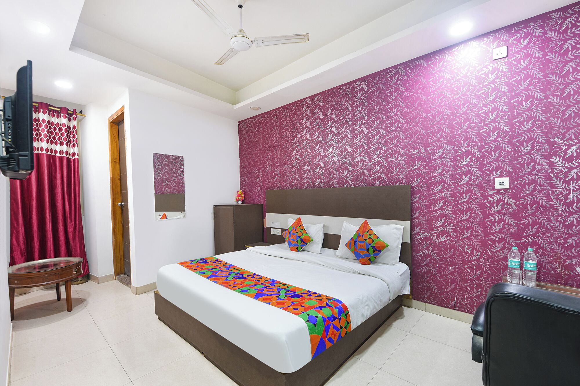 A hotel room with a bed, a desk, a chair, a television, and a bathroom.