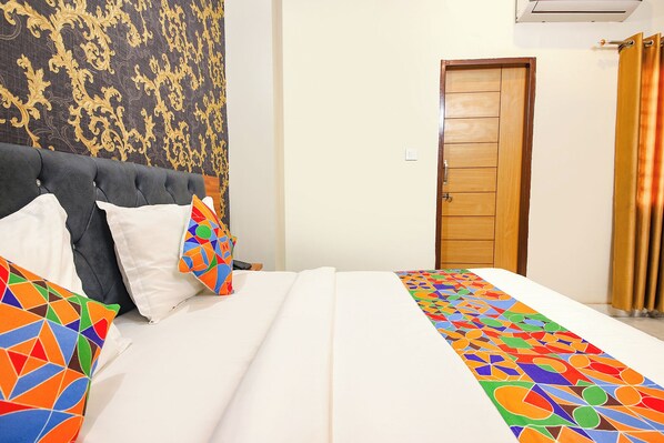 A hotel room with a bed, a wooden door, and a patterned wall. - Fabhotel Rudra (Rishikesh)