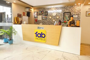 A reception desk with a 'fab hotels' sign, framed pictures, and a Buddha statue. - Fabhotel Rudra (Rishikesh)