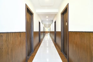 A long, narrow hallway with wooden paneling on both sides and a shiny tiled floor. - Fabhotel Rama (Indore)