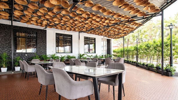 An outdoor dining area with brick flooring, grey chairs, and tables. - Fabhotel Rama (Indore)