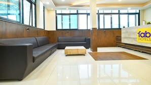 A hotel lobby with a reception desk, a sofa, and a wooden accent wall. - Fabhotel Rama (Indore)