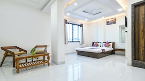A modern bedroom with a bed, a wooden bench, a window with curtains, and a ceiling fan. - Fabhotel Rama (Indore)