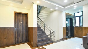 A modern hotel lobby with a wooden door, a staircase, and a reception desk. - Fabhotel Rama (Indore)