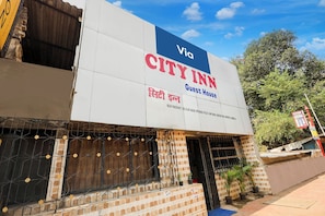 Placa da Guest House A CITY INN, com esquema de cores azul e branco, localizada perto de Panchvati SDCVijay Nagar, em frente ao Posto Policial de Oppomarol e da Marolosa Road.