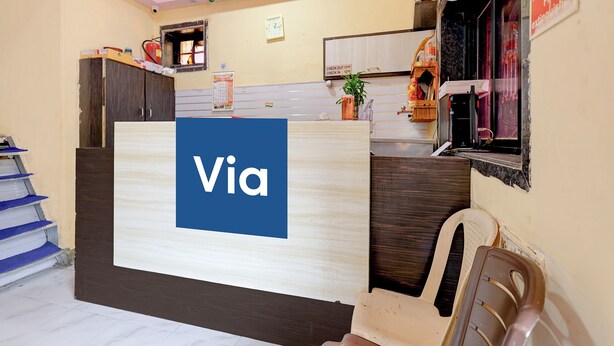 A reception desk with a 'Via' sign, a calendar, a fire extinguisher, and a window with a view of the outside. - FabHotel AK Residency (Mumbai)