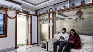 A reception area with a sofa, a clock, and a glass display case with decorative items. - FabHotel Om Guest House & Banquet (Kolkata)