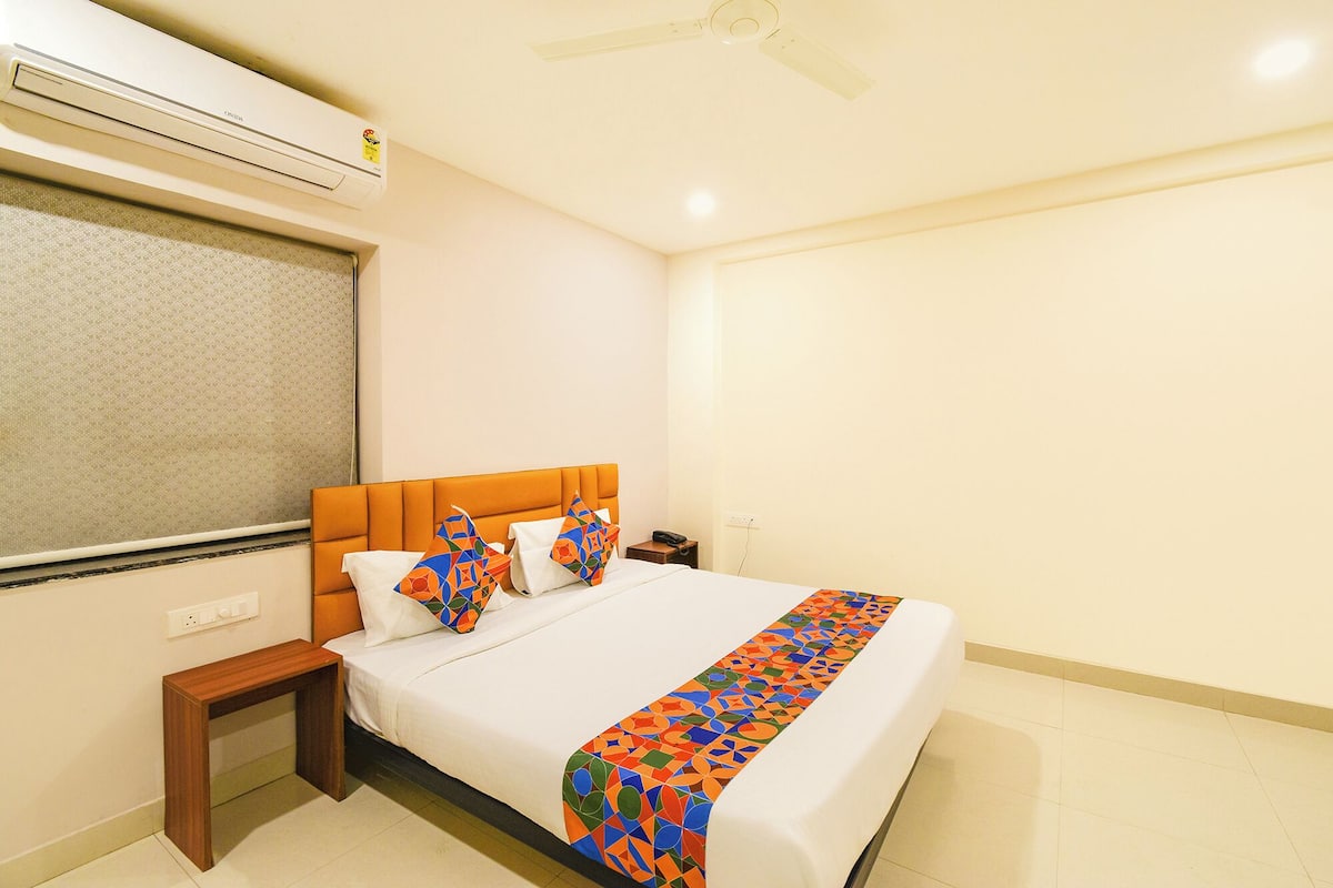 Een hotelkamer met een bed, een nachtkastje, een wandairconditioner en een plafondventilator.