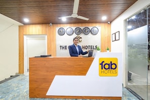 Una reception con un logo, un orologio e una ventola a soffitto nella hall di un hotel.