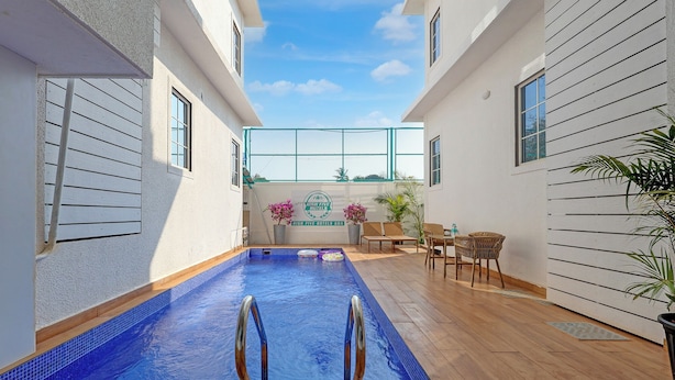 Un área de piscina con vistas despejadas del cielo, un cartel de High Five Hotels y un espacio de descanso con sillas y una mesa.