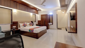 Una habitación de hotel moderna con una cama grande, un escritorio, una silla, un armario y un ventilador de techo.
