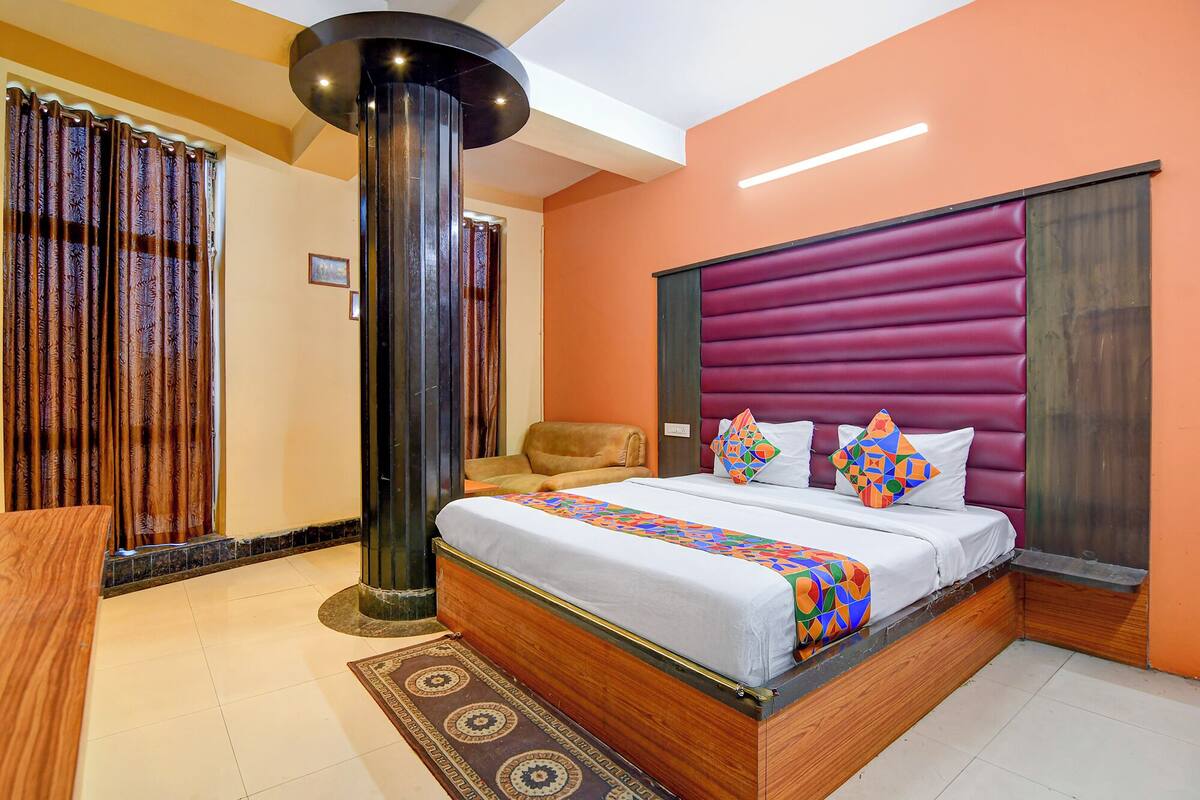 Un dormitorio moderno con una cama grande, cabecera de madera y un pilar decorativo.