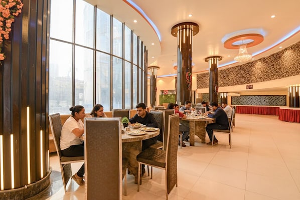 A modern dining area with round tables, high ceilings, and large windows.