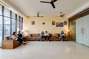 Eine geräumige Lobby mit hoher Decke, verschiedenen Sitzbereichen und Deckenventilatoren.