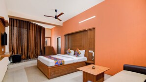 A hotel room with a bed, a small table, a chair, a ceiling fan, and a television. - Fabhotel Aqua Villa (Barasat)