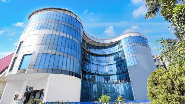 A modern building with curved glass facades and a white exterior. - Fabhotel Aqua Villa (Barasat)