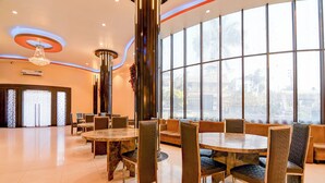 A spacious hotel lobby with a large seating area, a high ceiling with a modern chandelier, and large windows offering a city view. - Fabhotel Aqua Villa (Barasat)