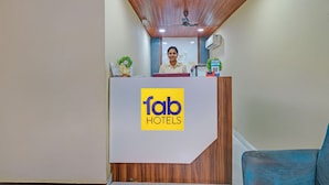 A reception desk with a logo for 'fab hotels' and a receptionist. - Fabhotel La Vista Inn Grand (Hyderabad)