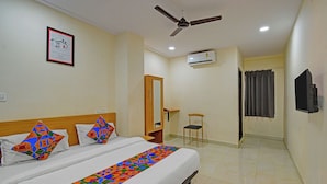 A hotel room with a bed, a ceiling fan, an air conditioning unit, a mirror, and a chair. - Fabhotel La Vista Inn Grand (Hyderabad)