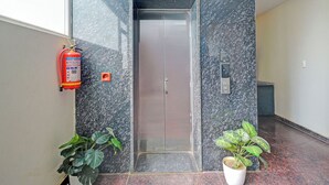 An elevator with a sign indicating the ground floor, a fire extinguisher, and two potted plants. - Fabhotel La Vista Inn Grand (Hyderabad)