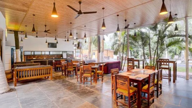 A spacious restaurant with wooden furniture, a tiled floor, and a ceiling fan. - FabHotel Bay Breeze - 800M From Morjim Beach (Morjim)