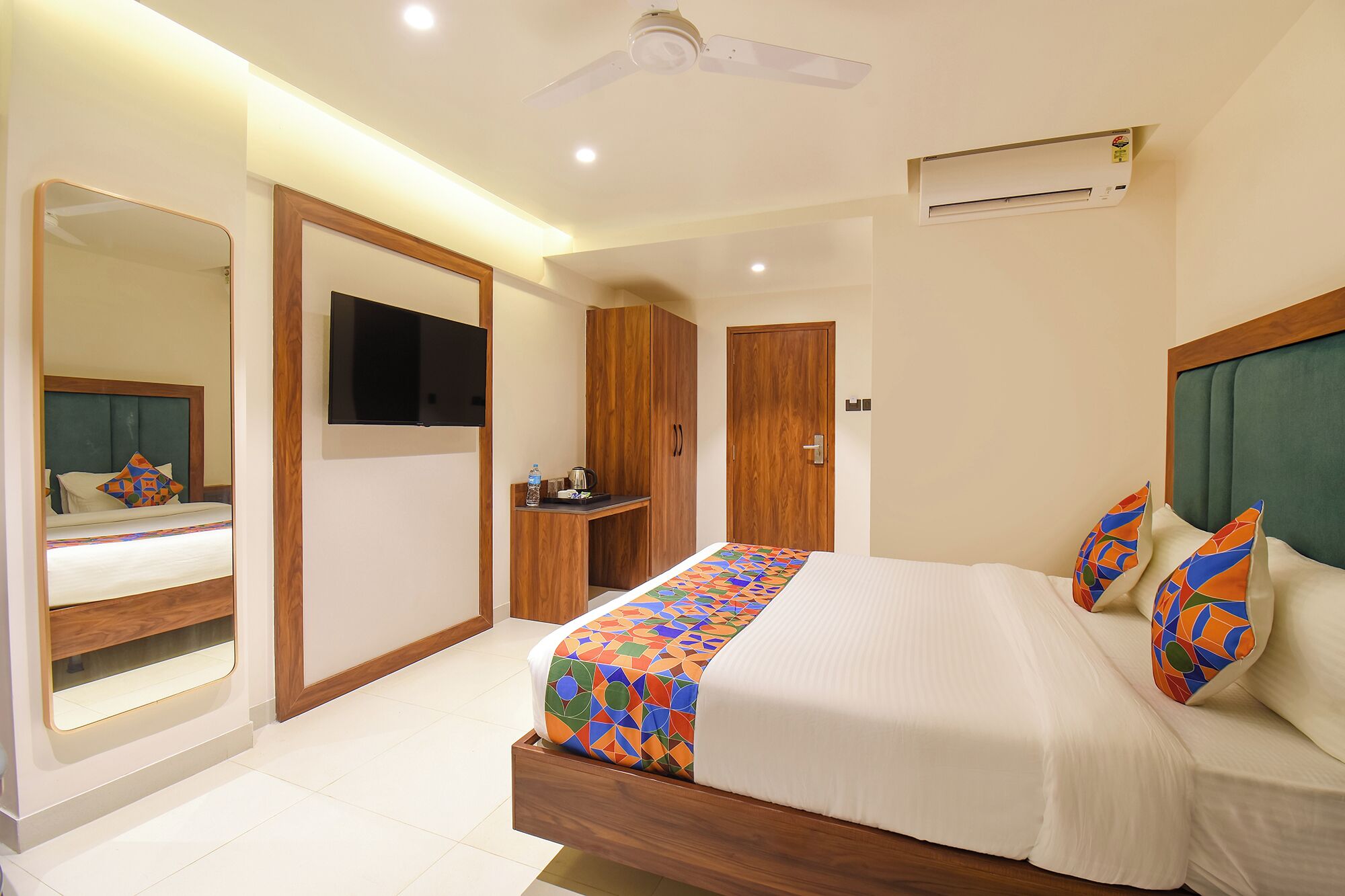 Una habitación de hotel moderna con una cama grande, televisión, armario y espejo.