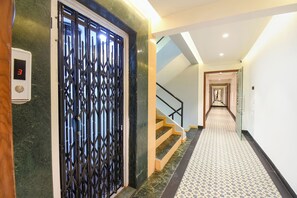 Un couloir d’hôtel avec un sol à motifs, un escalier et une grille en métal décorative.
