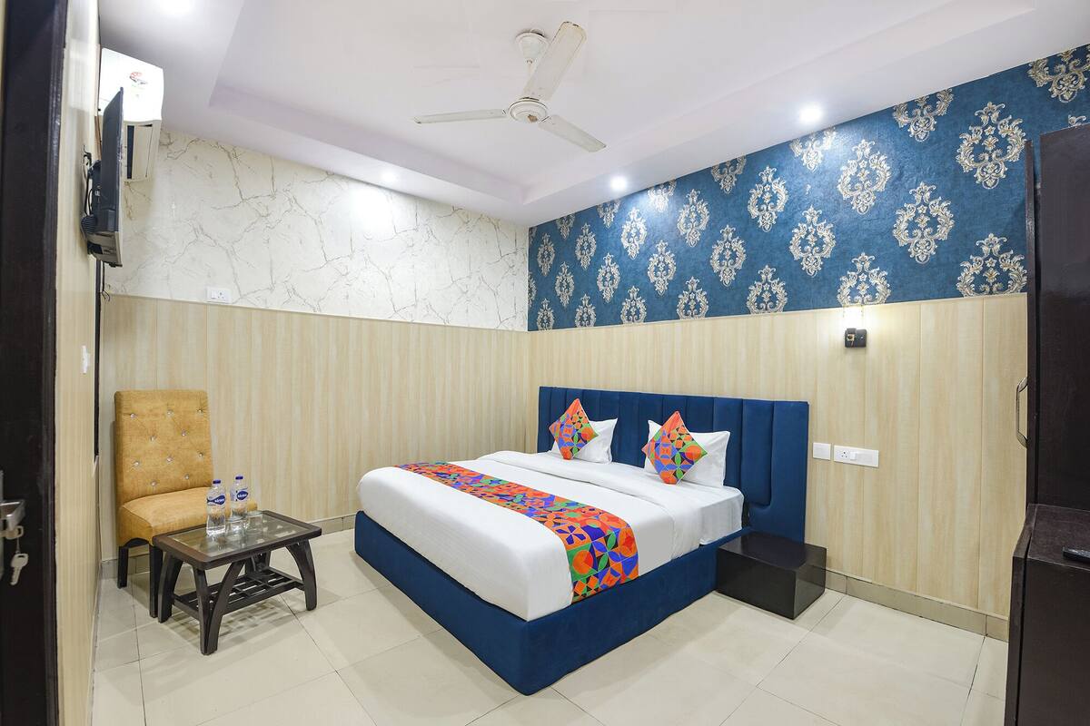 Une chambre d’hôtel avec un lit, une chaise, une petite table et un ventilateur de plafond.