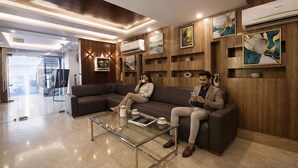 A modern living room with a sofa, a coffee table, and decorative wall art. - FabHotel Crown Residency - Near Lakhani Armaan Metro Station (Faridabad)