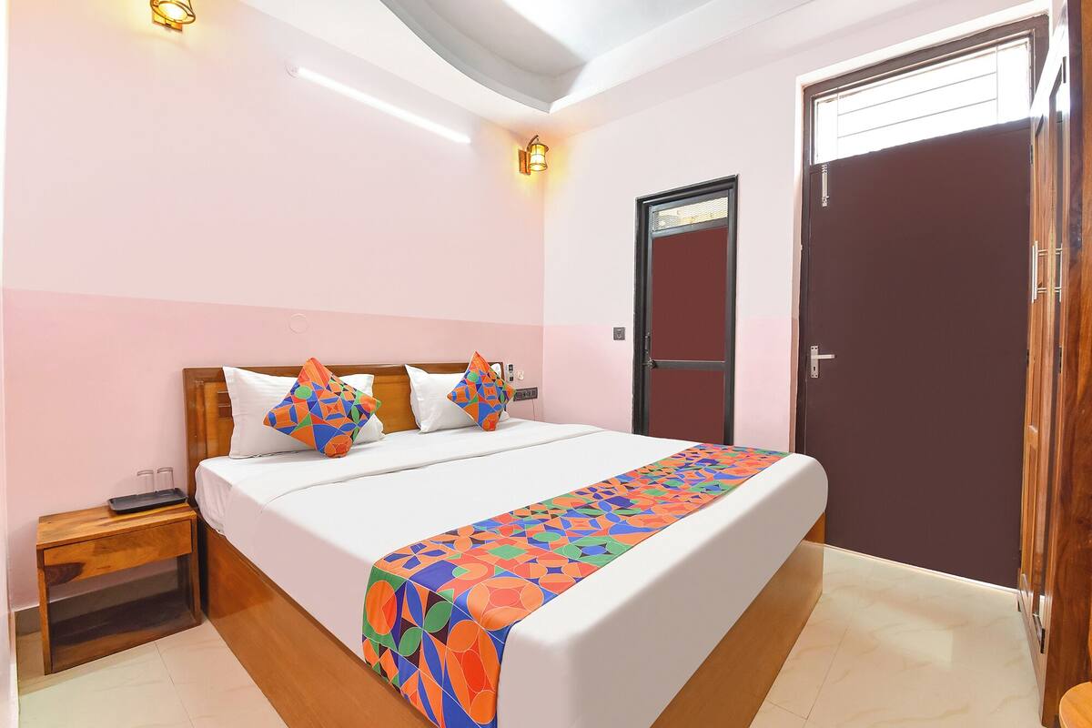 A bedroom with a bed, bedside tables, a door, and a light fixture.