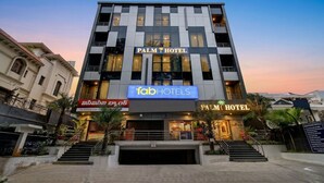 Un hôtel à plusieurs étages, avec une enseigne « Palm Hotel », une autre enseigne « fabHOTELS » et un escalier menant à l’entrée.