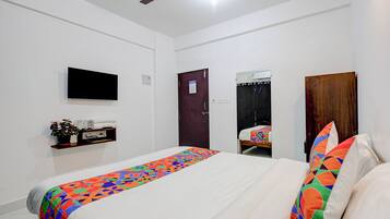 A bedroom with a bed, a TV mounted on the wall, a ceiling fan, a door, and a mirror.