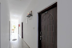 Un couloir avec une porte en bois sombre portant l’inscription « Crystal Bay, n° 104 », un extincteur et une étagère fixée au mur, sur laquelle se trouve un tableau encadré.