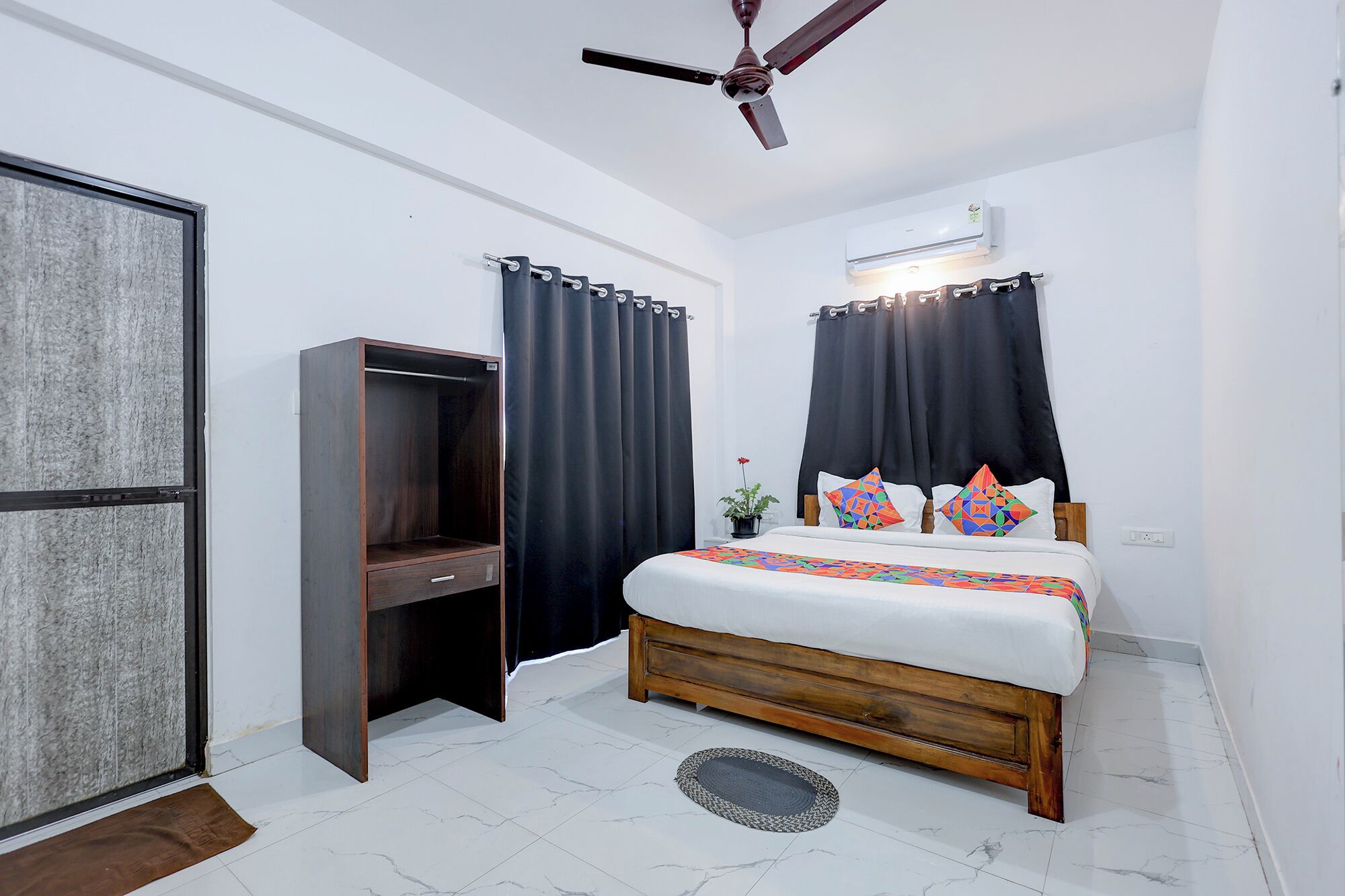 A bedroom with a bed, a wardrobe, a ceiling fan, and an air conditioning unit.