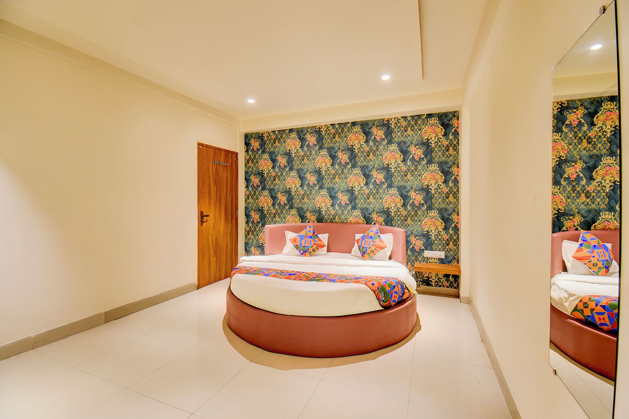 A bedroom with a round bed, a wooden door, and a patterned wallpaper.