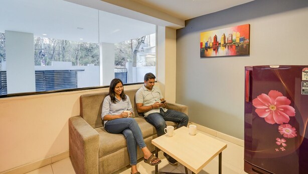 A modern room with a sofa, a table, and a refrigerator with a floral design. - Fabhotel White Ridge Gachibowli (Hyderabad)