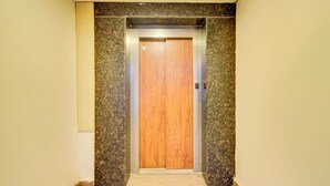 An elevator with a wooden door and granite walls. - Fabhotel White Ridge Gachibowli (Hyderabad)
