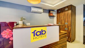 A reception desk with a 'fab hotels' sign, a potted plant, a wall-mounted air conditioner, and wooden cabinets. - Fabhotel White Ridge Gachibowli (Hyderabad)