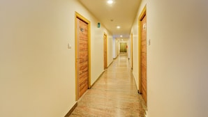 A hotel hallway with wooden doors on both sides, a marble floor, and a ceiling light. - Fabhotel White Ridge Gachibowli (Hyderabad)