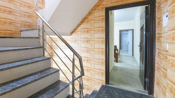 A staircase with metal railings leading to a door with a wooden panel wall. - Fabhotel Zen Stay (New Delhi)