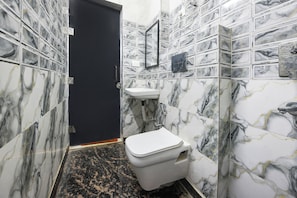 A bathroom with a toilet, sink, and black door. - Fabhotel Zen Stay (New Delhi)