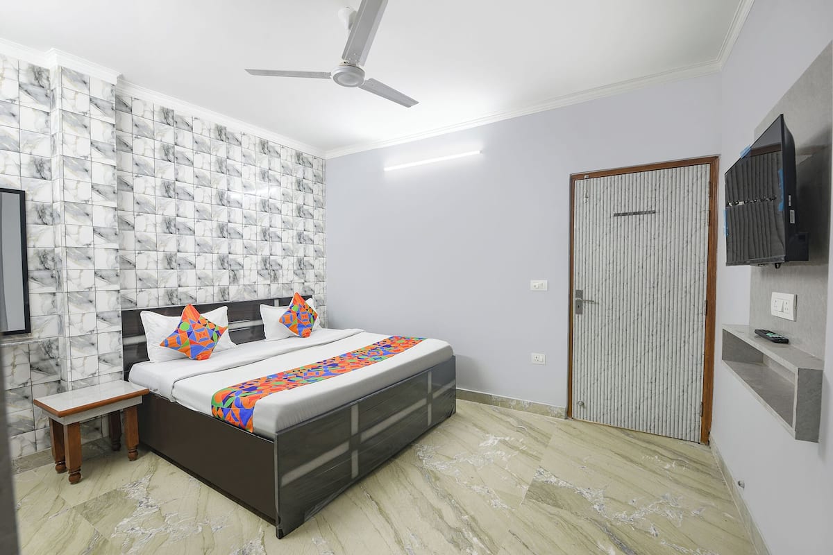 A bedroom with a bed, a nightstand, a TV, a ceiling fan, and a wardrobe.