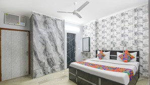 A bedroom with a bed, a ceiling fan, a wardrobe, and a bathroom door. - Fabhotel Zen Stay (New Delhi)