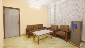 A room with a sofa set, a small table, a refrigerator, and a ceiling fan. - Fabhotel Zen Stay (New Delhi)