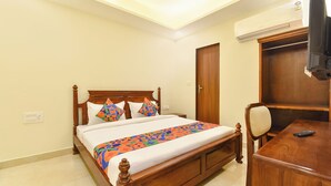 A neatly arranged hotel room with a wooden bed, a desk, and a wardrobe. - FabHotel Dream Prime (Jaipur)