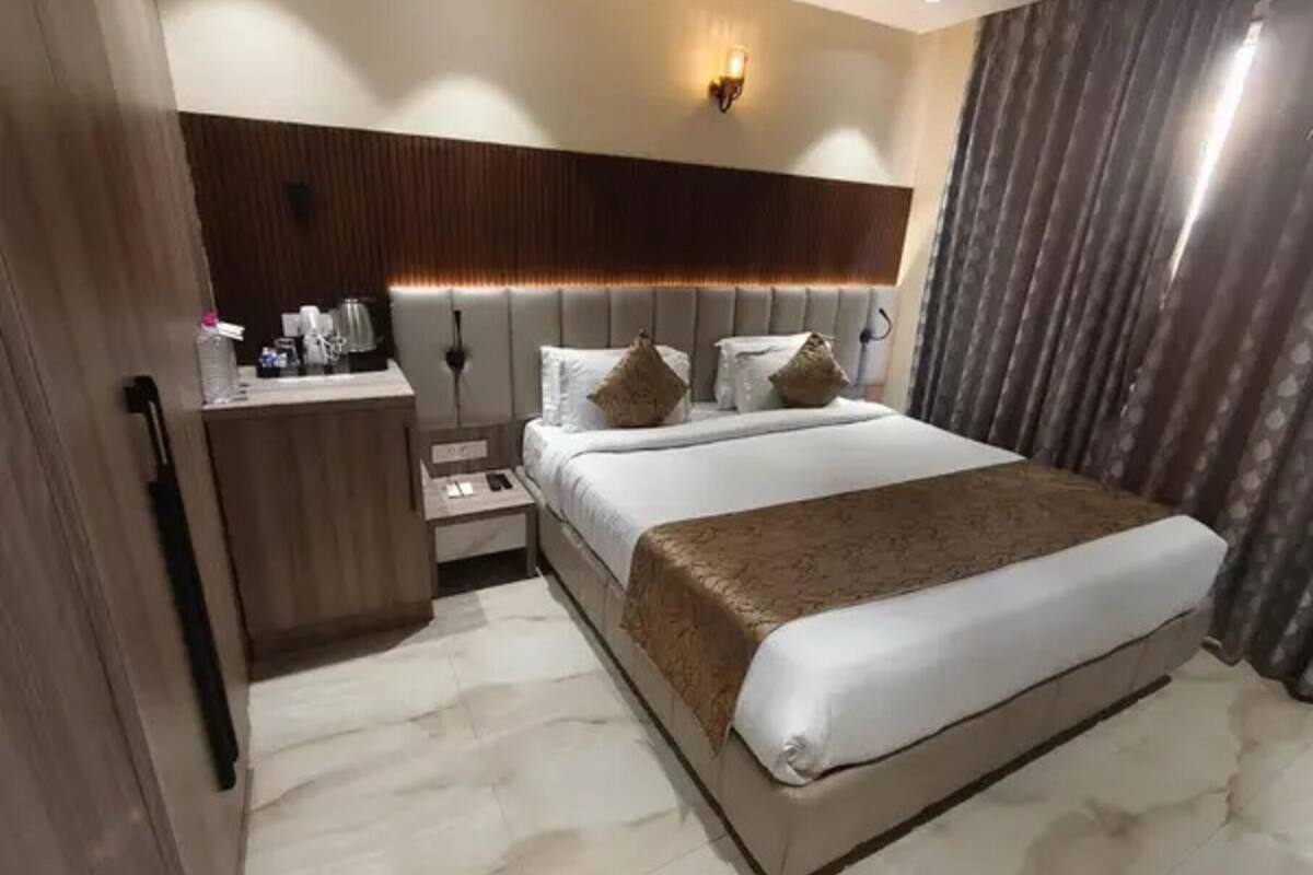 Una habitación de hotel moderna con una cama grande, una mesita de noche y un pequeño escritorio con lámpara.